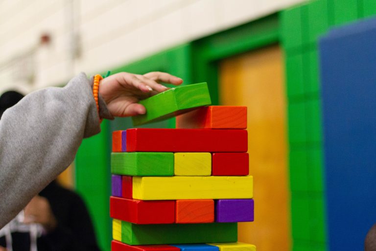 Child Building a Wooden Block Tower With Colourful Blocks